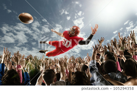 Professional american football player flies over hands of fans and catching a touchdown pass. Professional american football player flies over hands of fans and catching a touchdown pass. 105294358