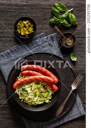 cooked sausages with coleslaw salad in black bowl 105295706