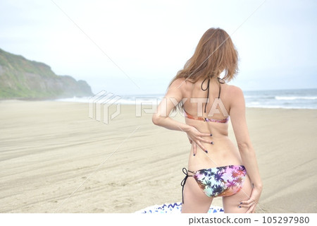 Young woman in bikini swimsuit posing on the beach Young woman in bikini swimsuit posing on the beach 105297980