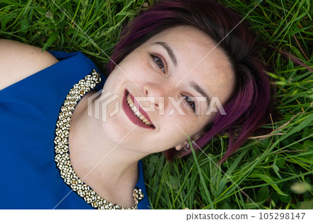 Happy young woman lying in grass in nature in summer 105298147