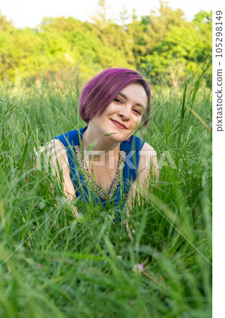 Happy young woman lying in grass in nature in summer Happy young woman lying in grass in nature in summer 105298149