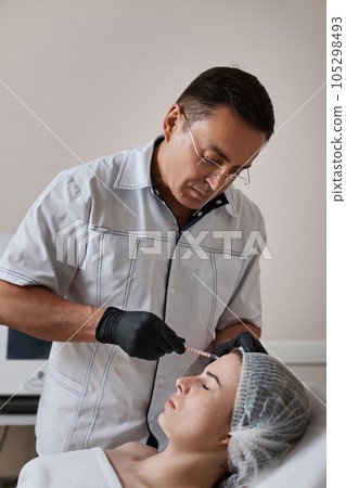 woman receives cosmetic botox injection in face. woman receives cosmetic botox injection in face. 105298493