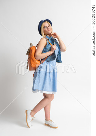 Woman in a summer dress with a hat and a backpack in the image of a tourist Woman in a summer dress with a hat and a backpack in the image of a tourist 105299745