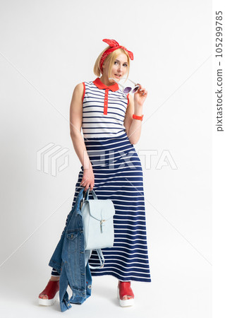 Woman in a striped dress with sunglasses and a denim jacket in her hand Woman in a striped dress with sunglasses and a denim jacket in her hand 105299785