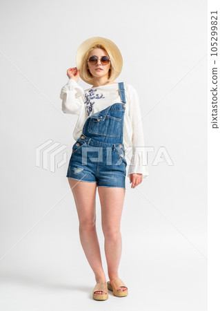 Woman in casual summer denim shorts, rustic blouse, straw hat and sunglasses 105299821