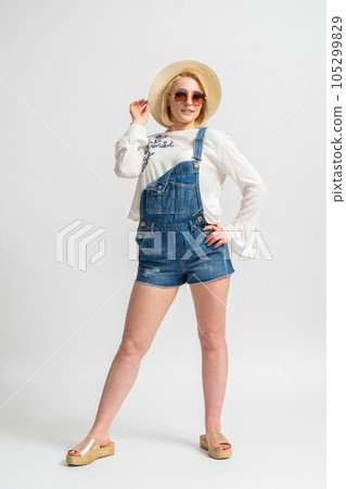 Woman in casual summer denim shorts, rustic blouse, straw hat and sunglasses 105299829