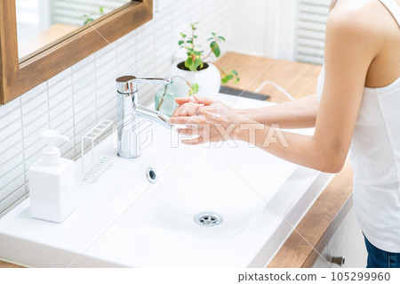 A woman washing her hands in the washbasin. A woman washing her hands in the washbasin. 105299960