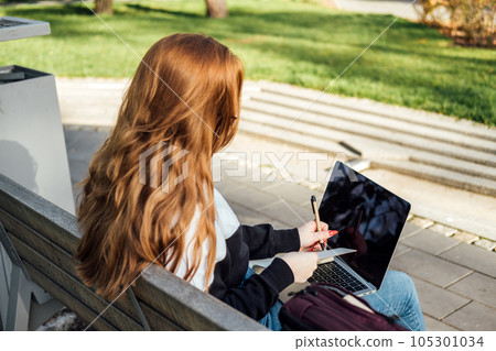 Personal Life Goals for Students. Successful students have goals. Succeeding in college and in life. Outdoor portrait of redhead student girl with laptop and backpack in city park Personal Life Goals for Students. Successful students have goals. Succeeding in college and in life. Outdoor portrait of redhead student girl with laptop and backpack in city park 105301034
