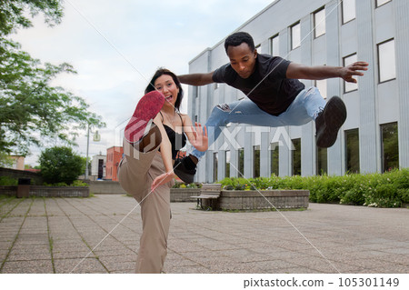 man jumping with a girl having one foot in the air, street style couple 105301149