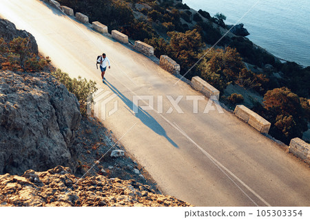 Man cyclist pedaling on a road bike outdoors in sun set Man cyclist pedaling on a road bike outdoors in sun set 105303354