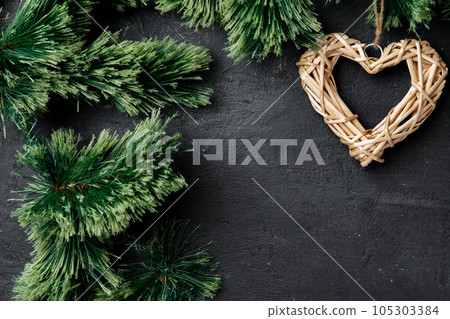 Fir tree branches with wooden heart on black 105303384