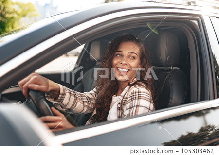 Young smiling woman driving a car in the city Young smiling woman driving a car in the city 105303462