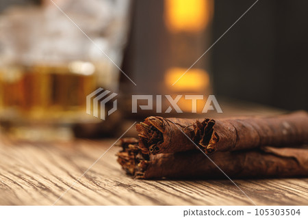 Three rolled cigarillos on wooden table close up Three rolled cigarillos on wooden table close up 105303504
