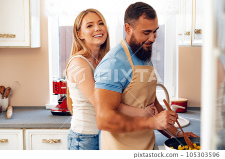 Couple in love preparing meal together in kitchen Couple in love preparing meal together in kitchen 105303596
