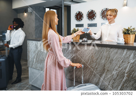 Young attractive woman with packed suitcase standing in hotel lobby 105303702
