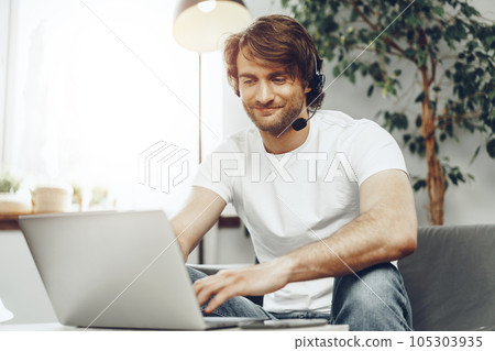 Young man businessman with headset working on laptop from home 105303935