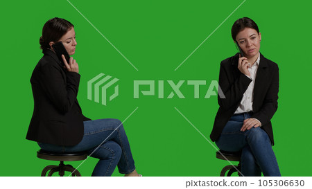 Close up of office worker talking on smartphone call over greenscreen background, using mobile phone and sitting on chair in studio. Young adult wearing formal suit on camera, telephone line. Close up of office worker talking on smartphone call over greenscreen background, using mobile phone and sitting on chair in studio. Young adult wearing formal suit on camera, telephone line. 105306630