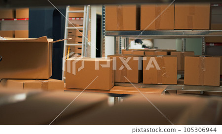 Empty storage space filled with stacks of merchandise and goods, shelves and racks of products in storehouse room. Warehouse used to deliver goods to customers working on logistics. Empty storage space filled with stacks of merchandise and goods, shelves and racks of products in storehouse room. Warehouse used to deliver goods to customers working on logistics. 105306944