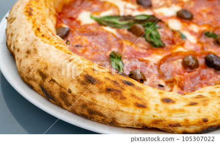 Pepperoni Pizza on Restaurant Plate, Salami Pizza with Olives, Tomatoes and Mozzarella Cheese 105307022