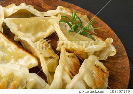 Gyoza Chinese Dumplings on Wood Plate, Fried Vegetable Jiaozi Macro, Chicken Momo Pile, Asian Gyoza Closeup 105307179