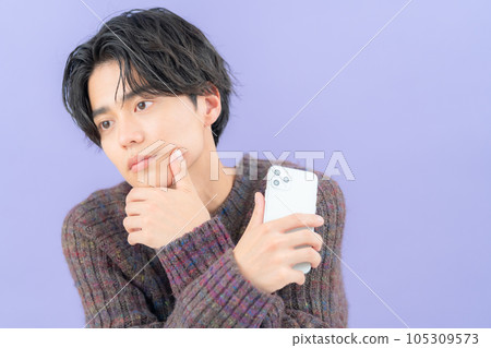 A young man wearing a purple back knit who operates a smartphone 105309573
