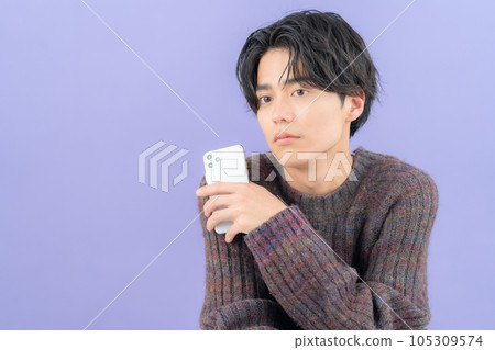 A young man wearing a purple back knit who operates a smartphone A young man wearing a purple back knit who operates a smartphone 105309574
