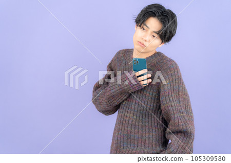 A young man wearing a purple back knit who operates a smartphone A young man wearing a purple back knit who operates a smartphone 105309580