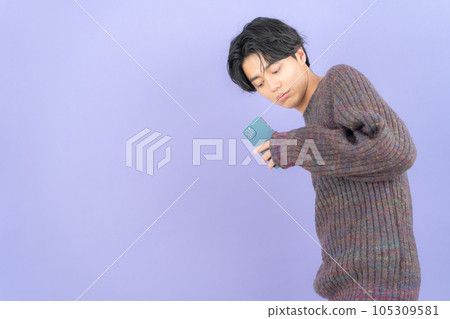 A young man wearing a purple back knit who operates a smartphone 105309581