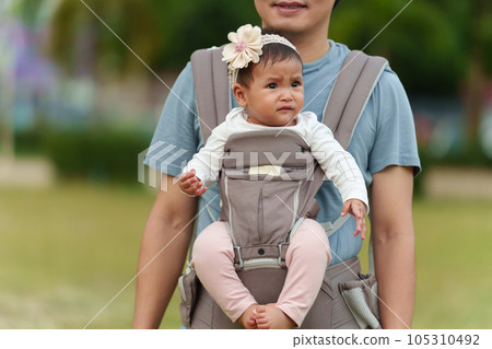 crying infant in baby carrier with father in park 105310492