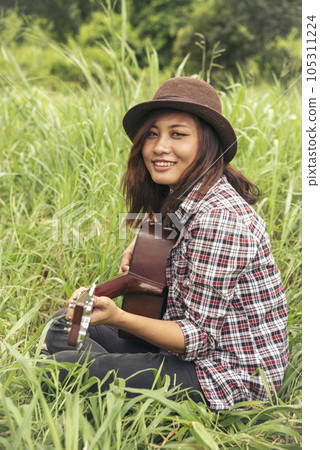 Young women playing acoustic guitar outdoor in green park. Woman person playing acoustic guitar music instrument at home, young Asian musician girl lifestyle in beautiful nature. Happy guitarist Young women playing acoustic guitar outdoor in green park. Woman person playing acoustic guitar music instrument at home, young Asian musician girl lifestyle in beautiful nature. Happy guitarist 105311224