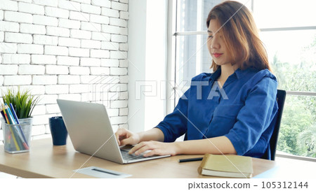 Asian Female freelance using laptop at home office desk. Woman reading financial graph chart Planning analyzing marketing data. Asian female people working office firm with business stuff, coffee cup Asian Female freelance using laptop at home office desk. Woman reading financial graph chart Planning analyzing marketing data. Asian female people working office firm with business stuff, coffee cup 105312144