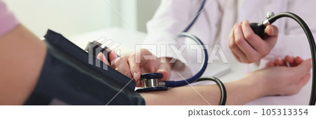 Doctor measuring blood pressure to patient using mechanical sphygmomanometer in clinic closeup Doctor measuring blood pressure to patient using mechanical sphygmomanometer in clinic closeup 105313354