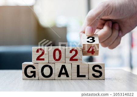 Businessman hand holding wooden cube with flip over block 2023 to 2024 Plans word on table background. Resolution, strategy, solution, goal, business and New Year holiday concepts 105314022