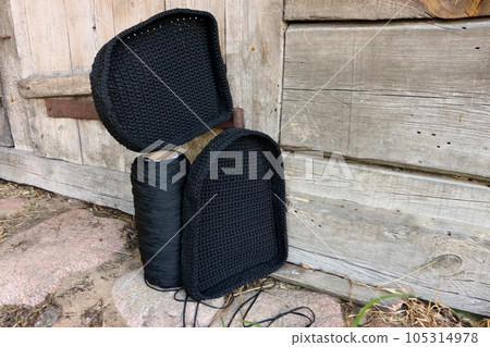 Homemade knitted black backpack. Backpack elements on vintage barn background. 105314978