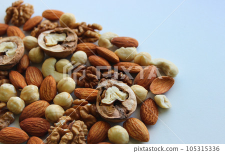 Triangle of scattered nuts of different varieties on a white background concept for backgrounds Triangle of scattered nuts of different varieties on a white background concept for backgrounds 105315336