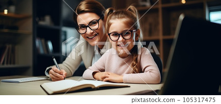 Happy child and adult are sitting at desk. Girl doing homework or online education 105317475