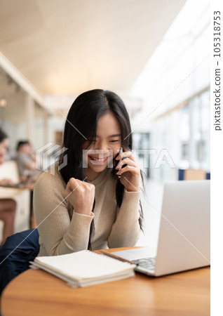 A portrait of a cheerful young Asian woman rejoicing after receiving good news over the phone 105318753