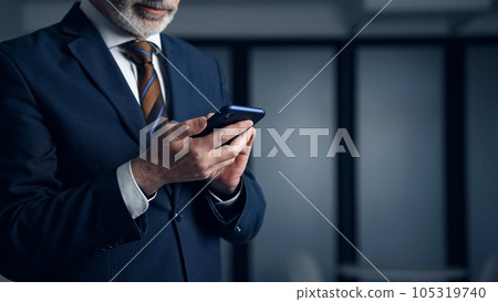一個男人在黑暗的辦公室裡使用智能手機 一個男人在黑暗的辦公室裡使用智能手機 105319740