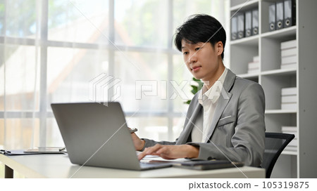 A handsome and smart Asian businessman focuses on his business work on his laptop 105319875
