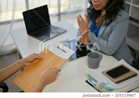 A senior businesswoman is talking about resigning and trying to compromise with a male employee A senior businesswoman is talking about resigning and trying to compromise with a male employee 105319907