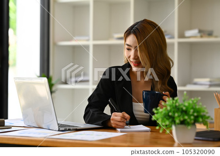 Millennial businesswoman in black suit using laptop, preparing economic report or presentation at workstation Millennial businesswoman in black suit using laptop, preparing economic report or presentation at workstation 105320090