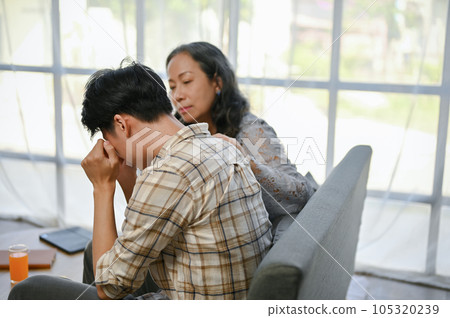 A caring Asian mom is trying to comfort and support her crying and sad son. care, family support A caring Asian mom is trying to comfort and support her crying and sad son. care, family support 105320239