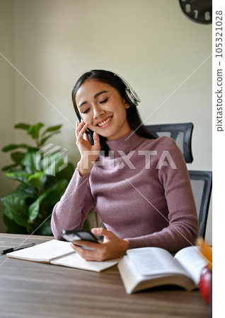 A portrait of a happy Asian woman enjoys listening to music through her wireless headphones 105321028