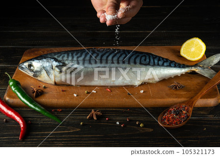 The chef adds salt to raw mackerel fish before cooking with ingredients and aromatic spices The chef adds salt to raw mackerel fish before cooking with ingredients and aromatic spices 105321173