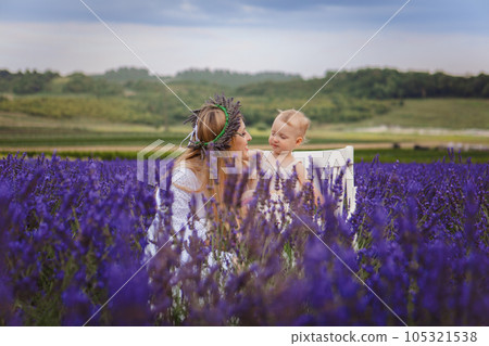 It is a picture of a small girl with her mother wearing a lavender wreath 105321538