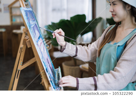 Concentrated woman in front of easel painting at home studio. 105322290