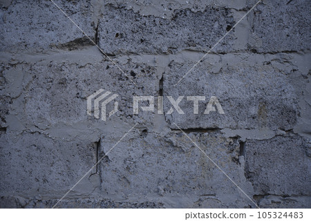 A gray wall of large blocks. Grey cinder block. The wall of an industrial building. A gray wall of large blocks. Grey cinder block. The wall of an industrial building. 105324483