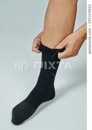 man is putting on his compression sock 105324822