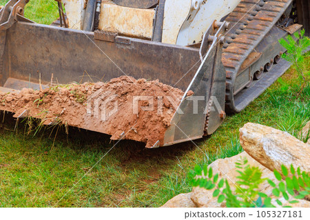 Mini bulldozer is efficiently working with earth, carrying out various landscaping tasks enhancing overall appearance of territory. Mini bulldozer is efficiently working with earth, carrying out various landscaping tasks enhancing overall appearance of territory. 105327181