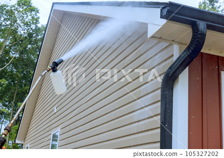 Water soap cleaner is sprayed onto siding houses by service worker, employing high pressure nozzles. Water soap cleaner is sprayed onto siding houses by service worker, employing high pressure nozzles. 105327202